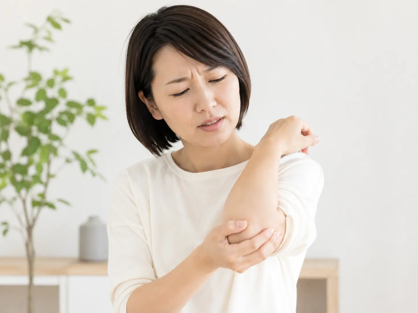 肘の外側を押さえ、テニス肘による痛みに悩む女性