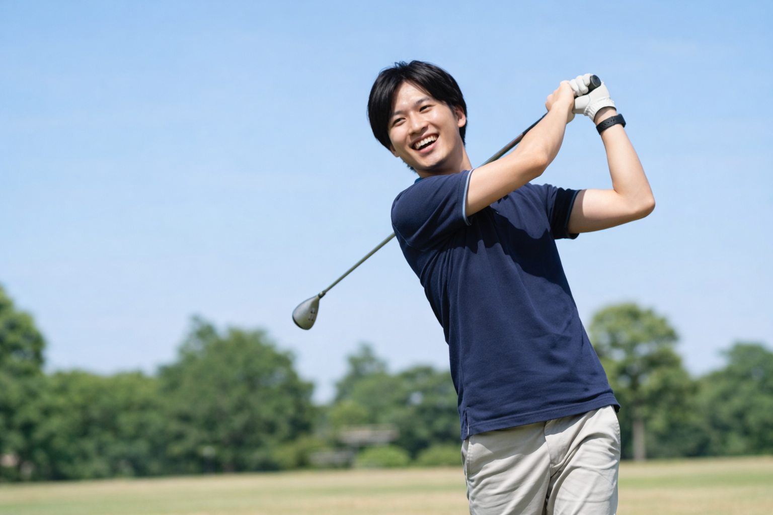 青空の下でゴルフを楽しむ男性。肘の痛みが改善し、思いきりスイングできるようになったイメージ