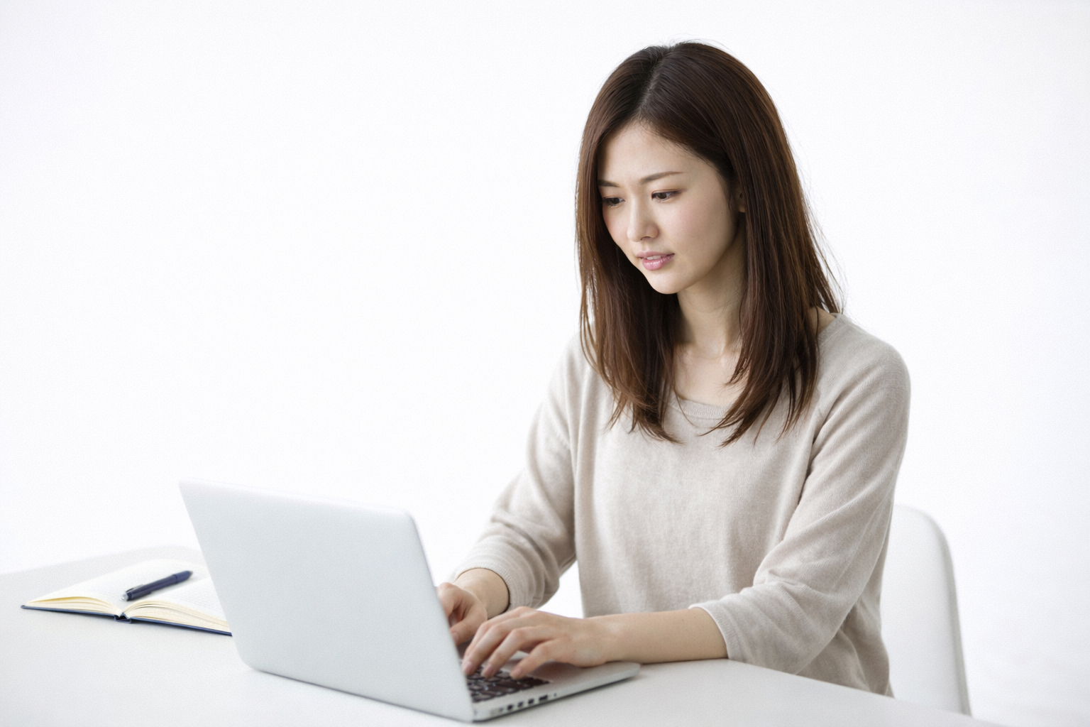 「ノートパソコンで作業する女性。長時間のデスクワークが肋間神経痛や姿勢不良の原因になることも」