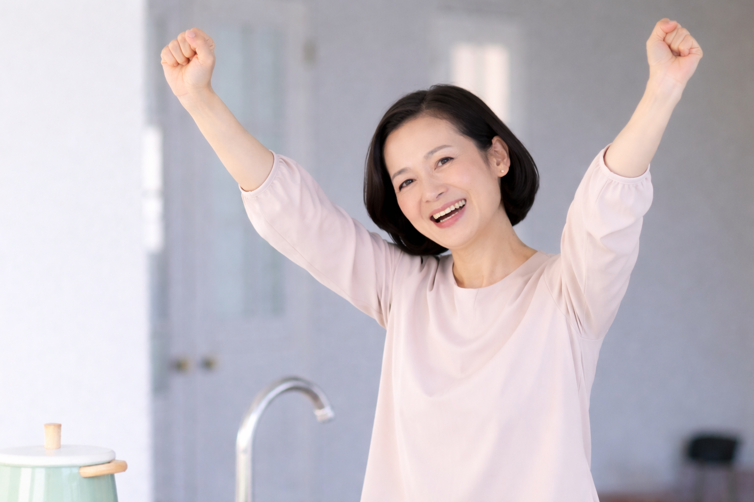 「両腕を元気に上げて笑顔を見せる女性。肩の痛みが改善し、快適に動かせるようになった様子」