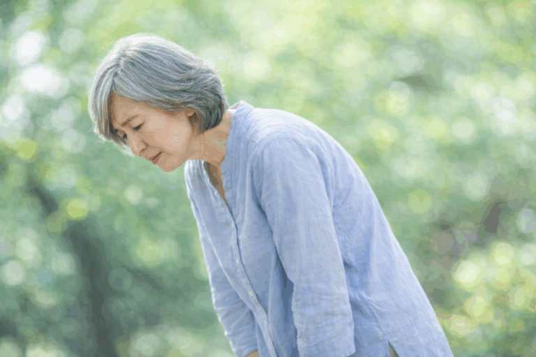 前かがみになって腰に手を当てる女性のイメージ