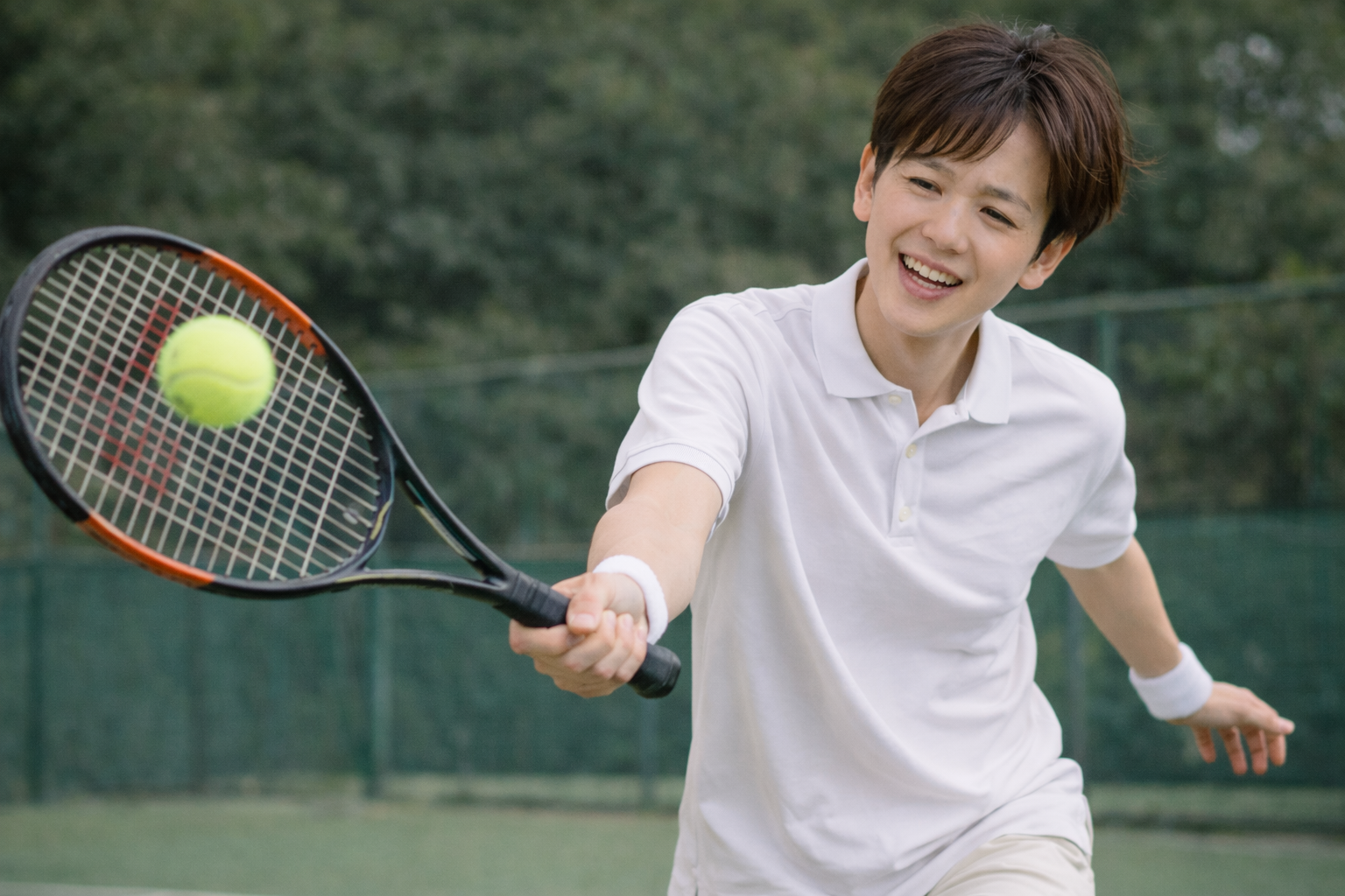 「テニスのプレー中にボールを打ち返す男性。手首を繰り返し使うスポーツが原因で起こるTFCC損傷や腱障害のリスクを示すシーン」