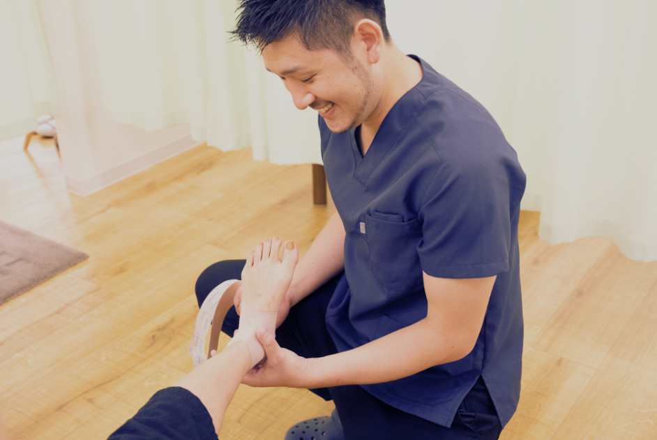 患者様の足の状態を丁寧に確認する柔道整復師・佐久間亮｜からだケア整骨院