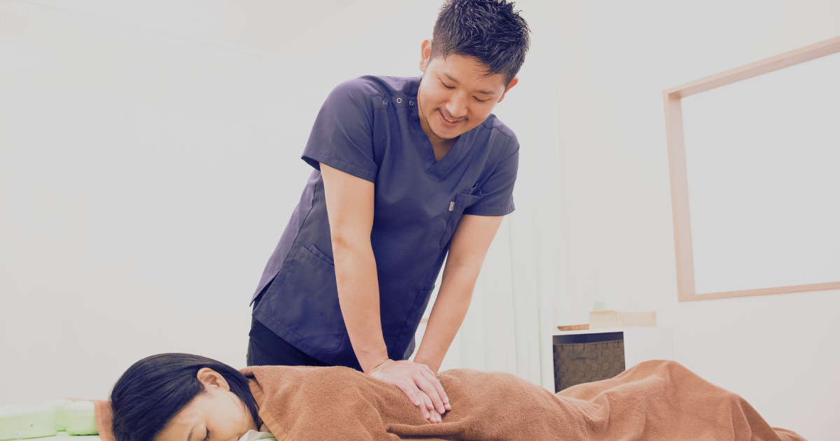 からだケア整骨院グループ代表・柔道整復師の佐久間亮が患者の背中に施術を行う様子