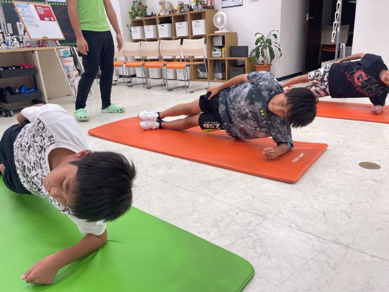マットの上で体幹トレーニングに取り組む子どもたち