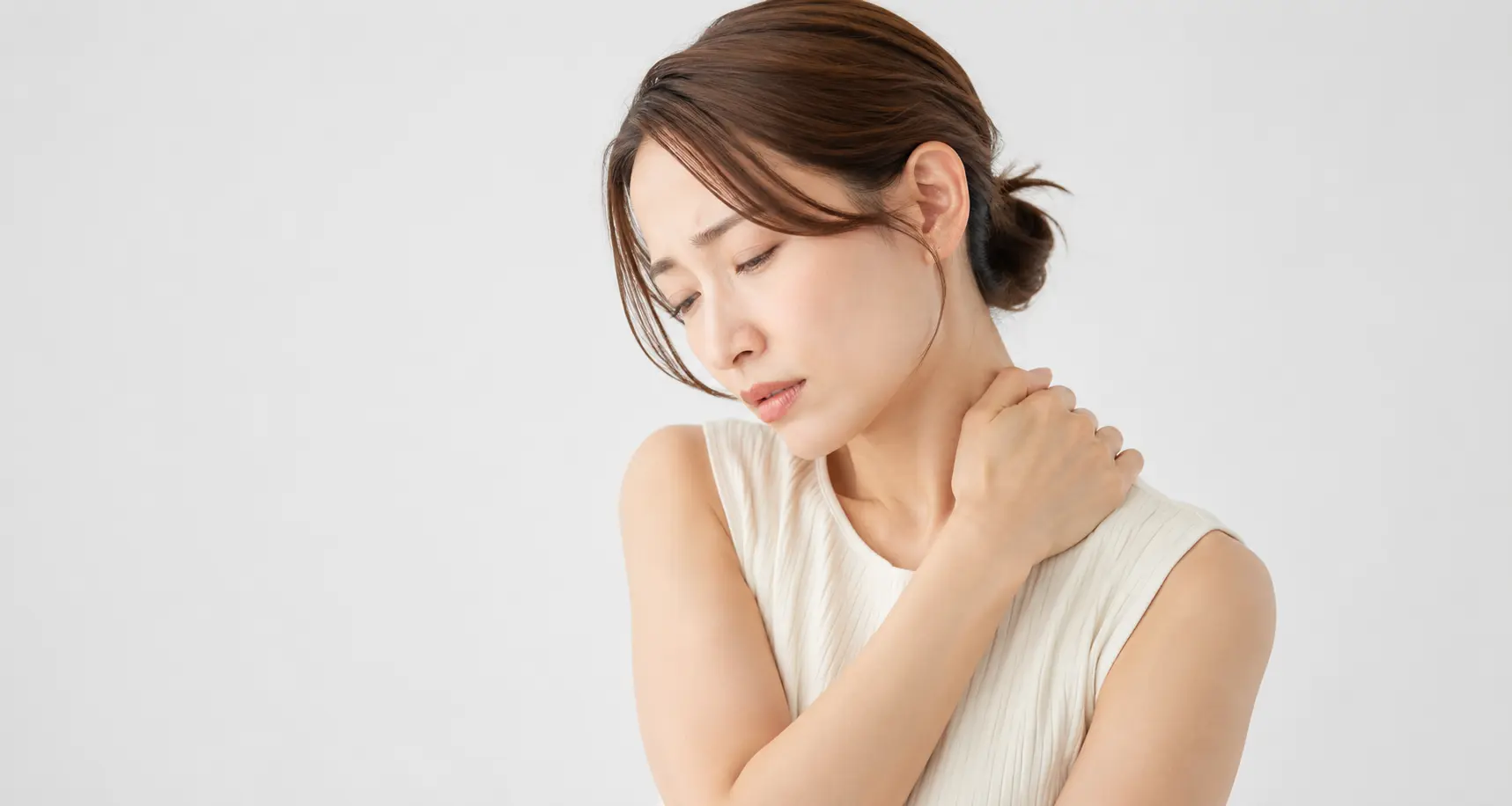 肩こりに悩み首肩を押さえる女性の写真|姿勢を正しているのに肩こりがつらい方へストレートバックとの関係を解説