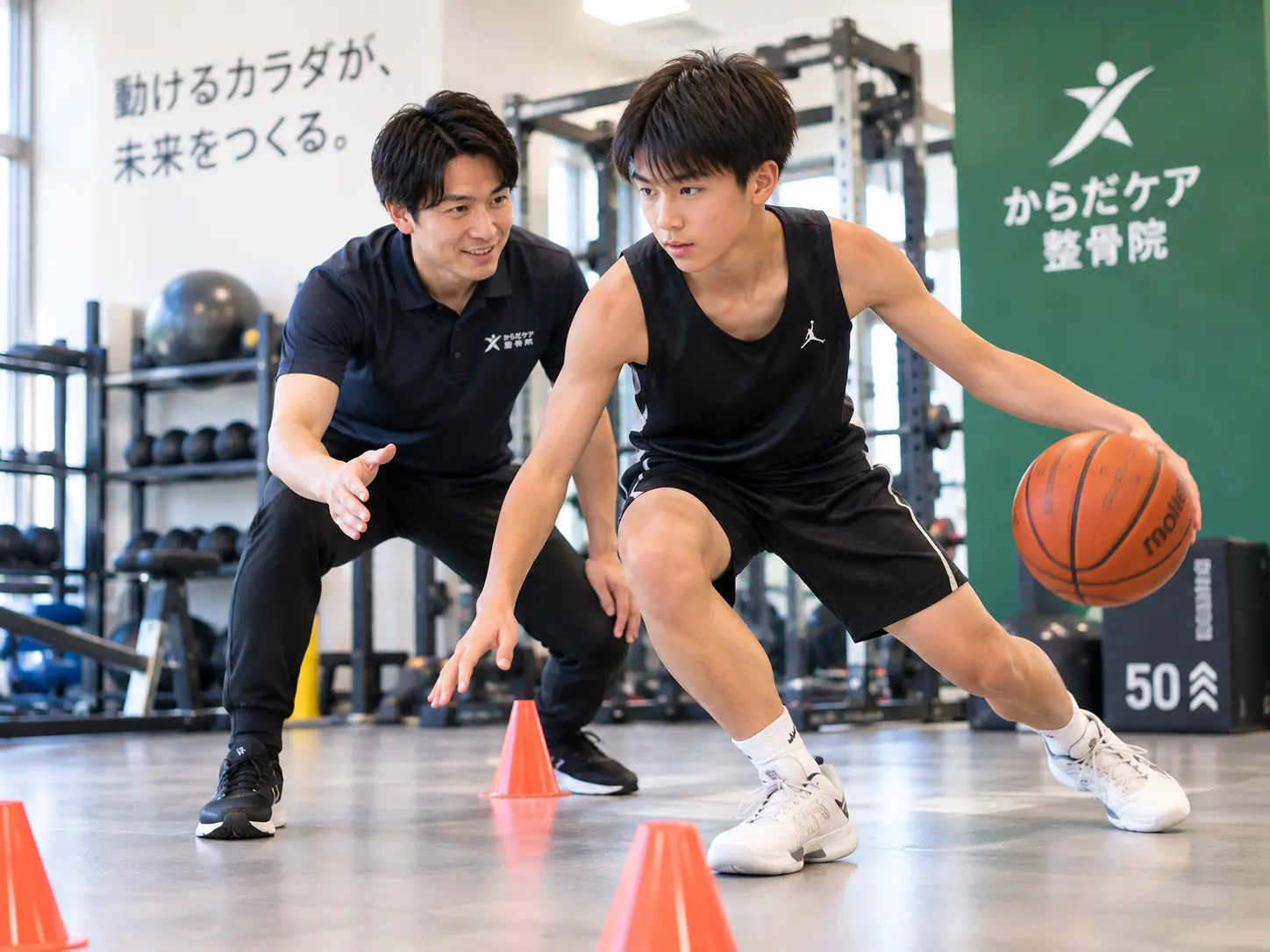 バスケットボール選手がスタッフの指導を受けながら、ドリブル動作を取り入れた俊敏性・切り返しトレーニングを行う様子。