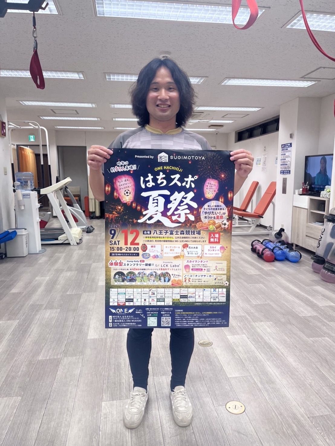 からだケア整骨院スタッフが2026年9月12日に八王子市富士森競技場で開催されるはちスポ夏祭のポスターを持ってイベント参加を案内している様子